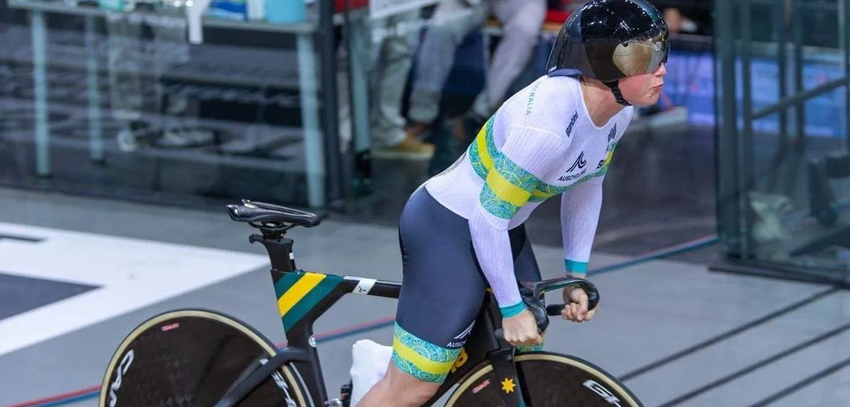 Australian track cyclist in aerodynamic cycling suit and helmet, riding a track bike during a race.