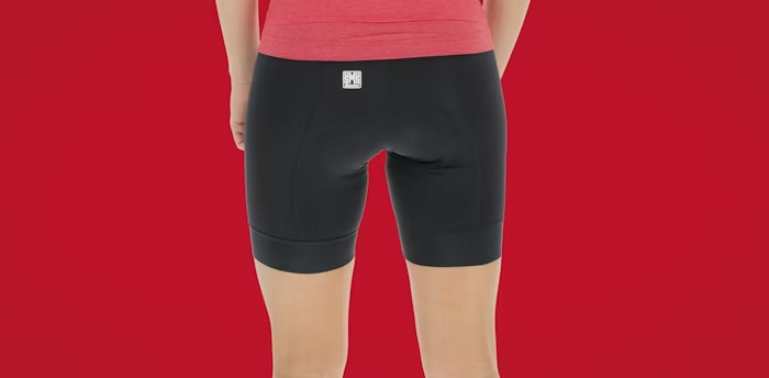 Back View of a Woman Wearing Black Cycling Shorts with a Red Top on a Red Background