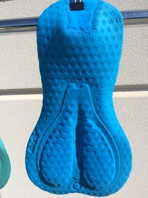 Bright blue cycling chamois pad hanging on a rail.